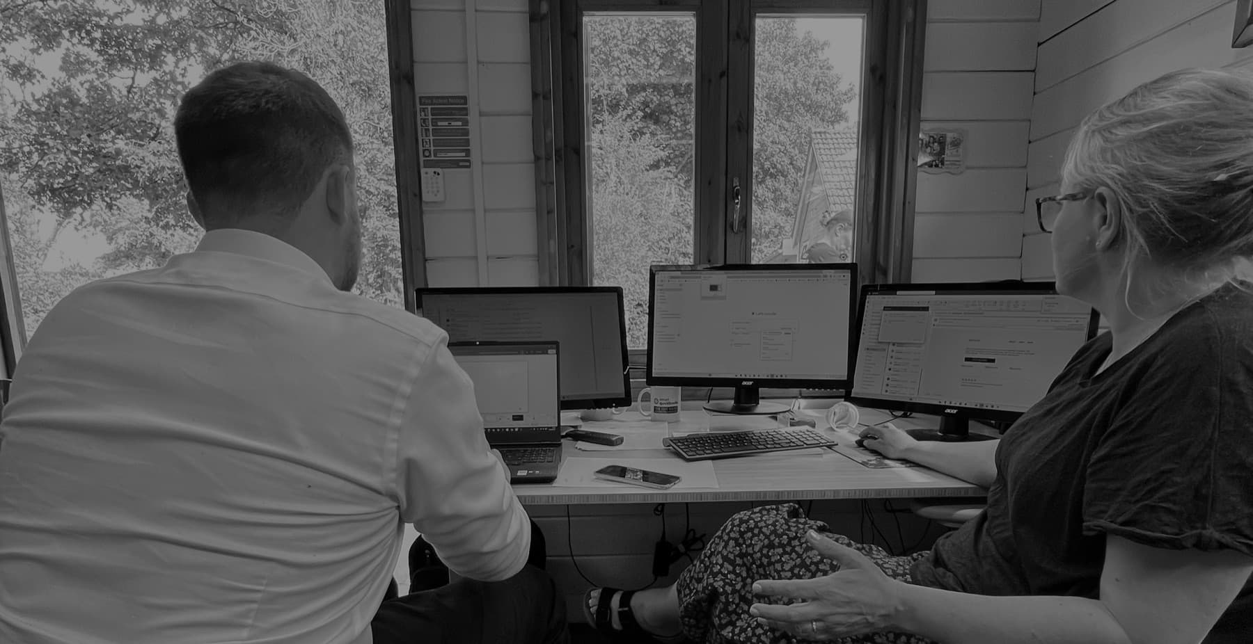 Will May working through screens with a member of staff at their desk in a small accountancy office
